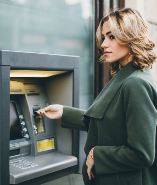 Frau hebt Geld am Geldautomat ab